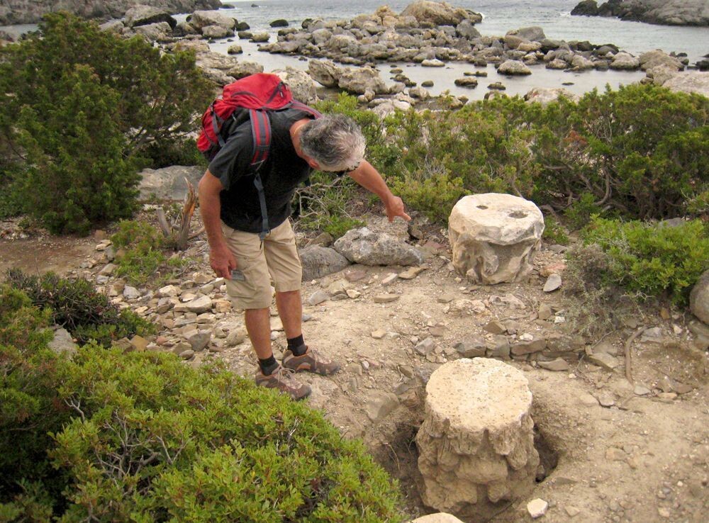 Wanderer betrachtet antike Säulenkapitelle an der Felsküste - Griechenland