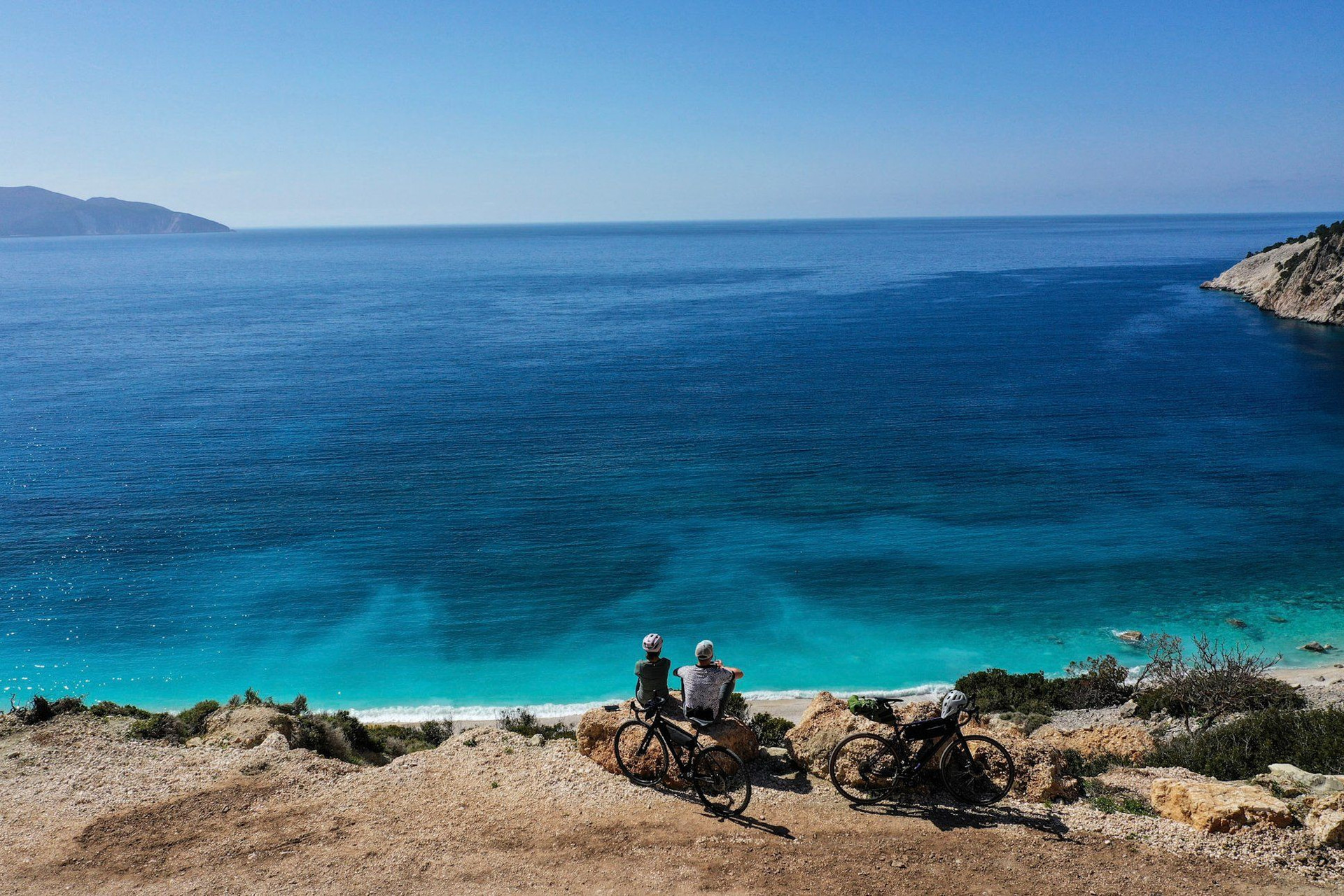 Cyclistes contemplant une crique turquoise - Méditerranée