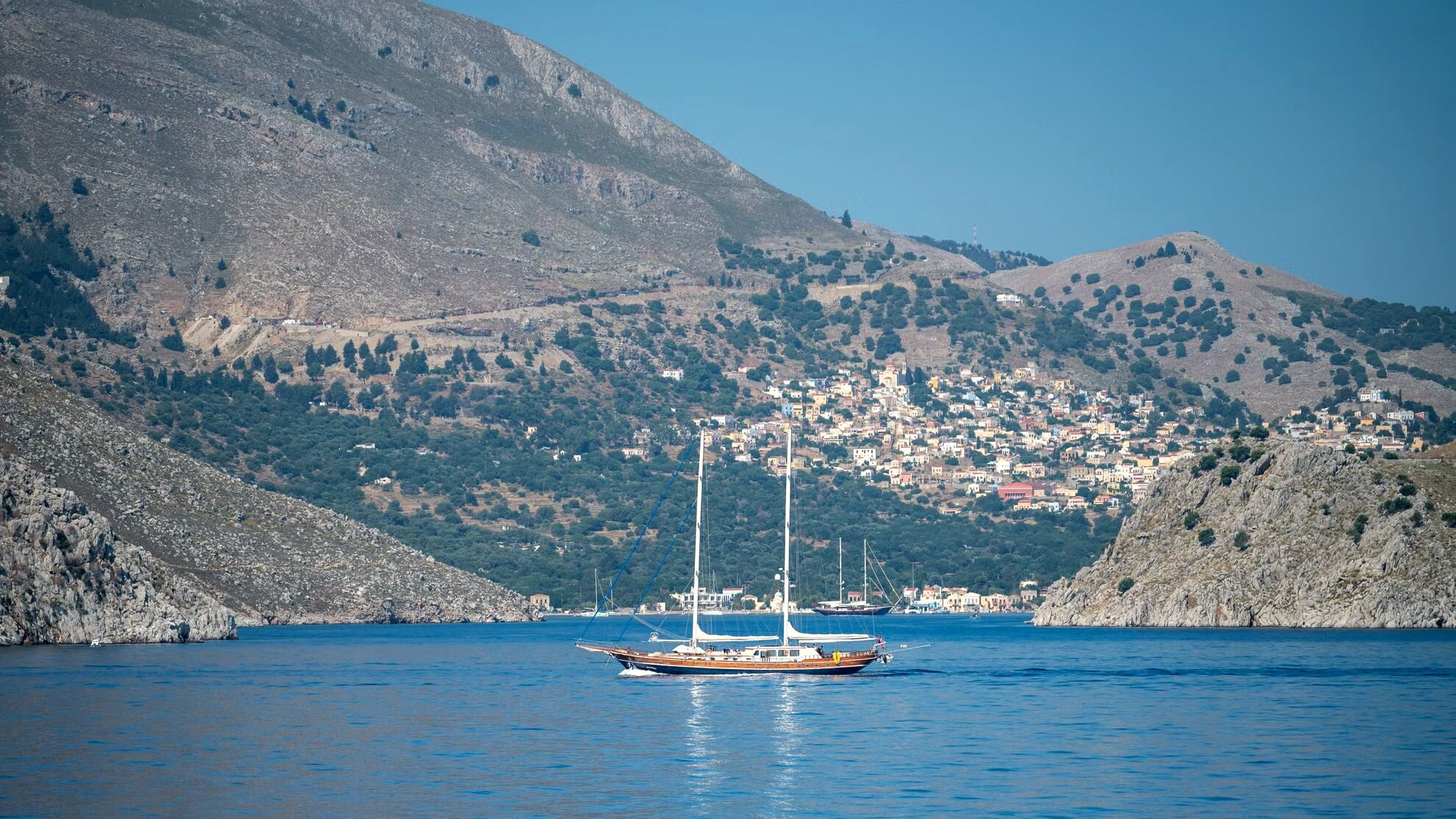 Segelboot vor Anker in einer Bucht am Fuß der Felswände – Symi – Griechenland